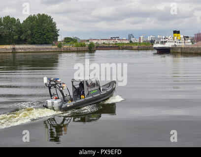 Un buque de patrulla de la policía se aleja del lado de la orilla del río y en el río Clyde en el muelle del Pacífico de Glasgow, Escocia, Reino Unido Foto de stock