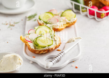Desayuno de queso crema, pepino y rábano sándwiches en una pizarra. Limpiar comiendo alimentos concepto. Foto de stock