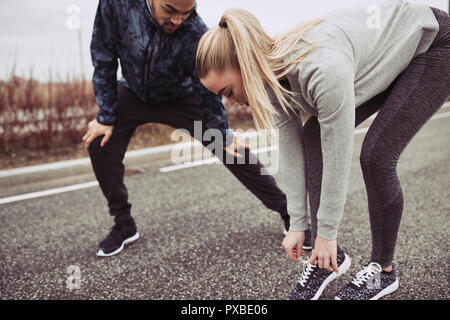 Mujer joven en ropa deportiva atar sus zapatillas antes de salir a correr  con ella boyriend a lo largo de una carretera en el país Fotografía de  stock - Alamy