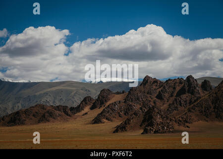 Accidentado paisaje mongol y formaciones rocosas. Las nubes y el cielo azul con Tsambagarav montaña en la distancia. Khovd, Mongolia Foto de stock