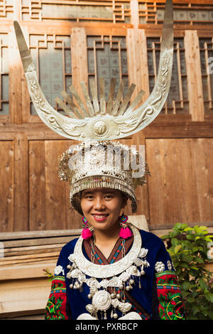 China, Guizhou, retrato de una joven mujer Miao vestida con un traje tradicional y un tocado Foto de stock