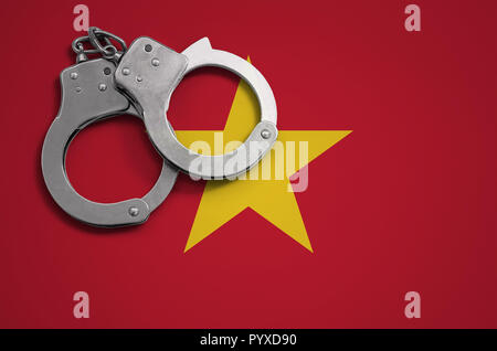 Bandera de Vietnam y esposas policiales. El concepto de crimen y delitos en el país. Foto de stock
