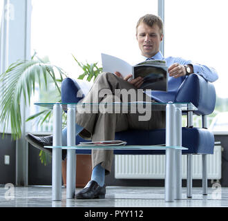 Empresario Leer revista en la sala de espera. Foto de stock