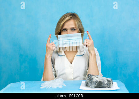 Una mujer trabajadora de laboratorio pone un rostro wadded respirador con un vendaje de gasa. Foto de stock