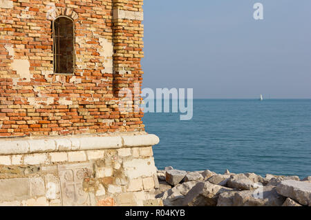 Detalle de la torre del campanario del Santuario de Nuestra Señora de los Angel en Caorle, Italia, con el mar Adriático en el fondo