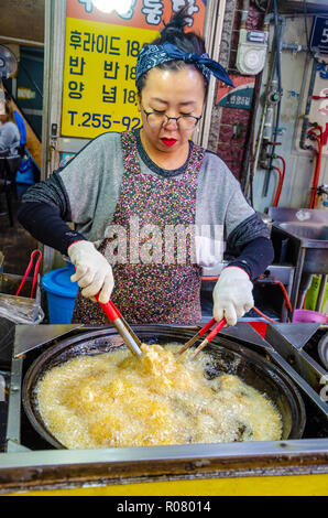 Una señora coreana cocineros pollo frito en Bupyeong Kkangtong Mercado en Busan, Corea del Sur. pollo frito es una popular, barata y sabrosa comida en la calle.