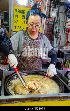 Una señora coreana cocineros pollo frito en Bupyeong Kkangtong Mercado en Busan, Corea del Sur. pollo frito es una popular, barata y sabrosa comida en la calle.