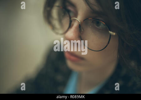 Retrato de mujer con gafas pensativo nublados y gotas de agua sobre ellos durante la lluvia en el atardecer.