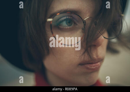 Retrato de joven mujer con gafas, pensativo en noche durante el crepúsculo.