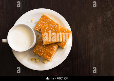 Vista superior del pan de maíz recién horneadas con queso y una taza de yogur en placa blanca sobre la mesa de madera Foto de stock