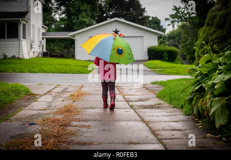 Una ni a de 4 a os camina en la lluvia sosteniendo un paraguas y