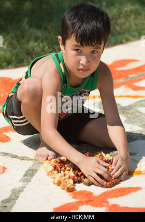 Niño juega el Shagai kazajo sobre la moqueta de la estepa, Astracán, Rusia. Foto de stock