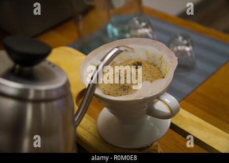 Un hervidor de agua se vierte en un filtro de café sentado en una taza. El barista está haciendo verter sobre el café. Foto de stock