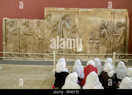 Teherán, Irán. Octubre 23, 2016 : escuela de niñas que asisten a la historia en frente del Persépolis bajorrelieve del rey Darío en el museo nacional. Foto de stock