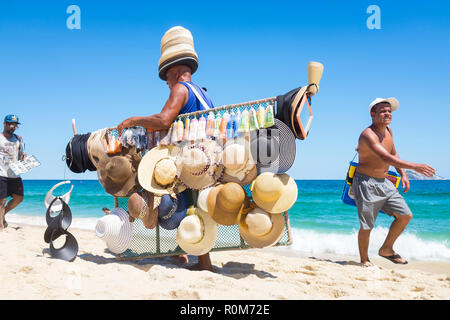 RIO DE JANEIRO - CIRCA Febrero, 2018: un proveedor brasileño vender sombreros de sol y protector solar pasa otros caminando por la orilla de playa de Ipanema Fotografía de - Alamy