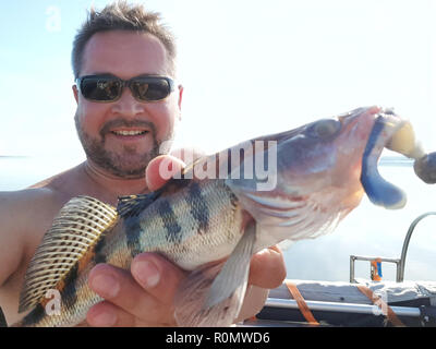 Hombre feliz con un pez en un viaje de pesca. Foto de stock