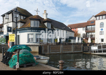 El Ship Inn junto al puerto, en Lymington Lymington, Hampshire, Reino Unido, con redes de pesca y un barco Foto de stock