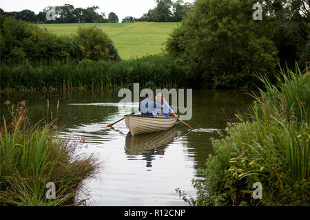 Pareja madura en bote a remo en el lago rural Foto de stock