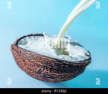 Con leche de coco splash sobre un fondo azul, salpicaduras de leche de coco
