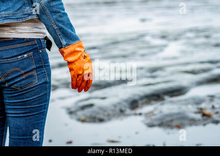 Un hombre con guantes naranjas recogiendo basura en una Un hombre con guantes naranjas recogiendo basura en una