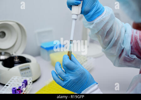 Prueba de ADN en el laboratorio. Un técnico de laboratorio chorreando sangre en un tubo de ensayo de un dispensador. Foto de stock