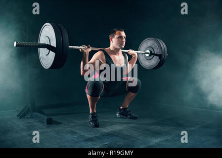 Powerlifter en ropa deportiva haciendo sentadilla con barbell en el