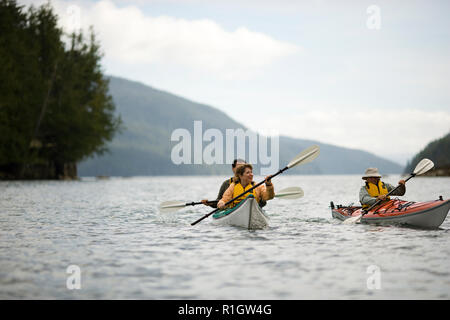 Adulto medio par kayak con su hijo adolescente sobre un lago. Foto de stock