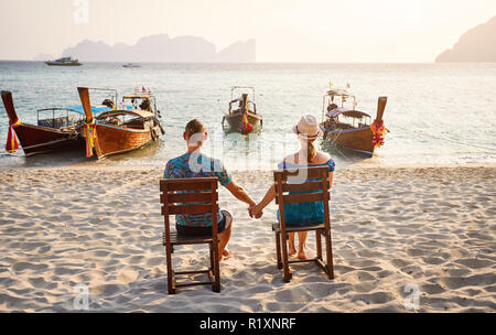 Pareja joven sentado en las sillas en la playa tropical de la isla Phi Phi en el sur de Tailandia. Concepto Travel Magazine.
