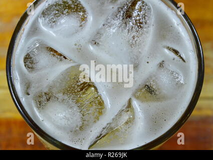 La cerveza y el hielo en el vaso en la mesa Foto de stock