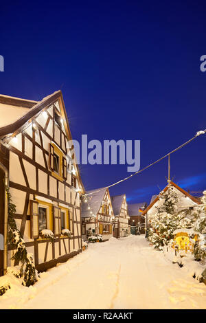 Una antigua calle de la aldea de casas con entramado de madera y decoración de navidad en la noche durante las nevadas en Lachen, Neustadt an der Weinstrasse, Alemania.