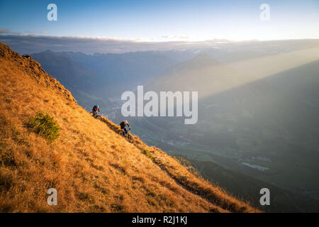 El hombre y la mujer el ciclismo de montaña en los Alpes austriacos al atardecer cerca de Gastein, Salzburgo, Austria