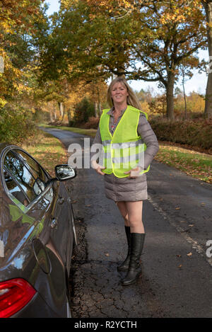 Mujer automovilista por su coche poniendo en una chaqueta de seguridad reflectantes Foto de stock