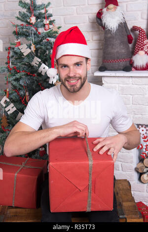 La mañana antes de navidad. entrega de regalos de navidad. feliz santa  hombre. compras navideñas online. escena de año nuevo con regalo de árbol.  hombre con sombrero de santa mantenga el regalo