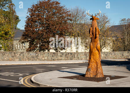 Madera tallada de venado. Una escultura creativa de una red stag saltar en el aire, tallada totalmente desde un árbol existente. Irlanda, en el condado de Kerry, Killarney. Foto de stock