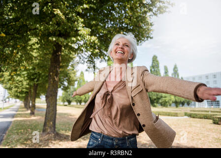 Feliz mujer mayor con los brazos estirados en un parque