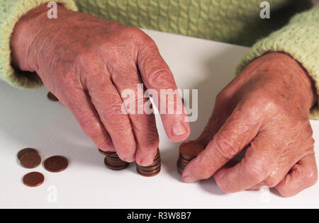 Las manos de la mujer son la celebración de unas monedas de euro. Pensión, la pobreza, los problemas sociales y el tema de la vejez. El ahorro. Foto de stock