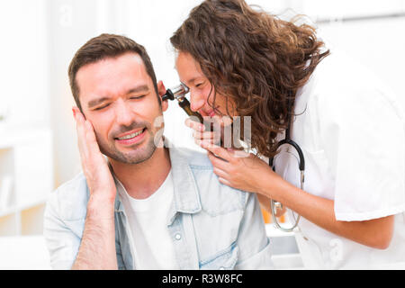 Atractiva joven doctor comprobación de la oreja del paciente Foto de stock