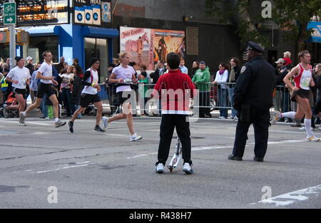 La Ciudad de Nueva York, NY, EE.UU. Nov 2008. Muchacho sobre scooter multitud elude la barricada para conversar con un policía uniformado cubriendo la Maratón de la ciudad de Nueva York. Foto de stock