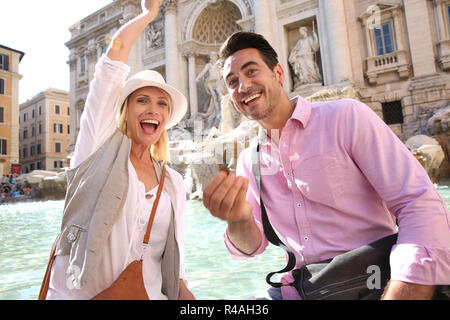 Par de turistas echando monedas en la Fontana de Trevi el agua Foto de stock