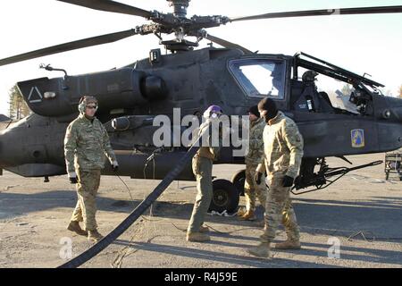 Soldados del ejército de EE.UU. asignados al 1er Batallón, 3º Regimiento de Aviación, la 12ª Brigada de Aviación de Combate, y una marina de los EE.UU. asignados a las operaciones aéreas, la empresa Marina Escuadrón de Apoyo ala 271 de combustible del ejército de los Estados Unidos un helicóptero de ataque AH-64 Apache durante una misión de reabastecimiento conjunta de colaboración entre el ejército de los Estados Unidos y la Infantería de Marina en apoyo del ejercicio Trident coyuntura 18, en Vaernes Air Station, Noruega, el 30 de octubre, 2018. Coyuntura Trident 18 es un ejercicio de capacitación multinacionales que enfatiza la disposición y la cooperación entre los Estados Unidos y sus aliados y socios europeos para garantizar los sombreretes Foto de stock
