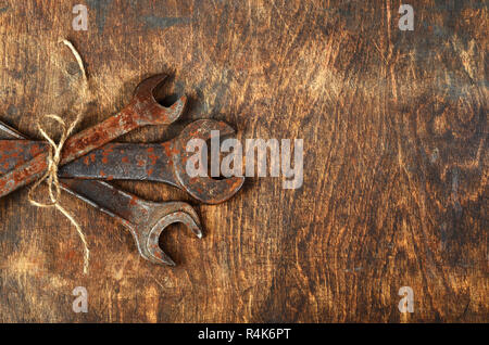 Montón de metal oxidado herramientas llave tumbado sobre mesa de madera oscura atados con una soga áspera ramo para hombre real