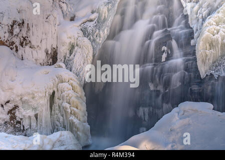 Colorido invierno vista sobre la cascada con agua suave, carámbanos, hermosos patrones de agua congelada y ventisqueros Foto de stock