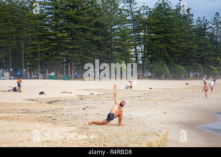 Hombre haciendo ejercicio y estiramientos en la playa de Burleigh Heads en Gold Coast, Queensland, Australia Foto de stock