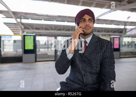 Empresario indio hablando por teléfono en la estación de tren Foto de stock