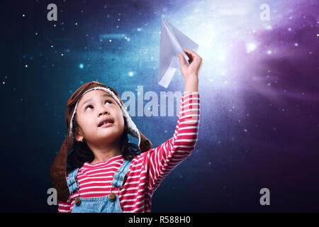 Bella asiática niña divirtiéndose con avión de papel juguete Foto de stock