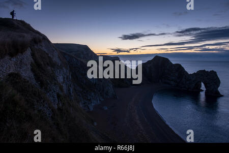 Un fotógrafo, prepara su cámara para el amanecer en Puerta de Durdle sobre la Costa Jurásica de Dorset
