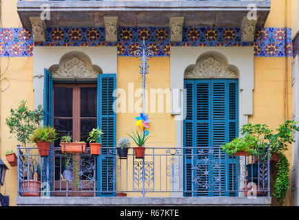 Ventanas adornadas con contraventanas azules de madera, esculturas y mosaicos florales y plantas en macetas en los balcones en el Barrio Gótico de Barcelona, España Foto de stock
