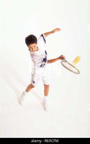 Retrato, Ganzfigur, Junge mit kurzen braunen Haaren, 12 Jahre, weisser Tenniskleidung beim Schlagen des balles mit dem Schlaeger Foto de stock