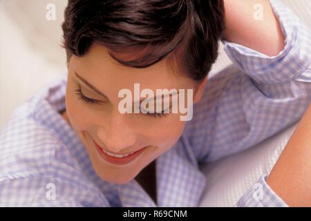 Retrato, Innenraum, Nahaufnahme, junge Frau mit kurzen braunen Haaren und braunen Augen im-weiss Pijama karierten hellblau Foto de stock