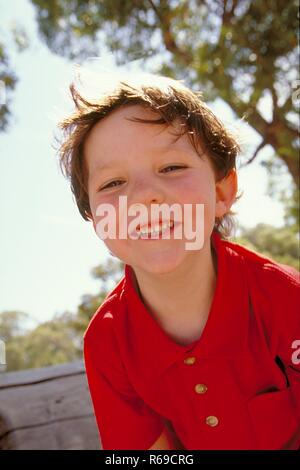 Piscina, Retrato, 6-Halbfigur mit kurzen jaehriger Junge braunen Haaren, mit rotem bekleidet Polohemd, zeigt lachend Zaehne sena Foto de stock